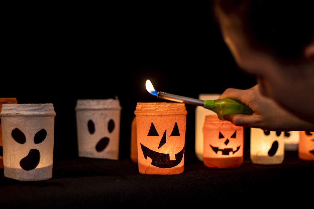 girl lights candle inside glass jars decorated halloween